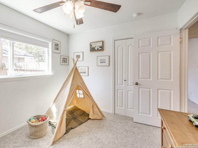 game room with a ceiling fan, light carpet, and baseboards