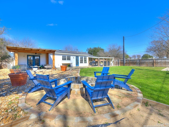 rear view of property with an outdoor fire pit, french doors, fence, a yard, and a patio area