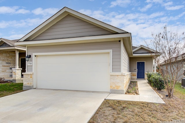 view of front facade with a garage, stone siding, cooling unit, and concrete driveway