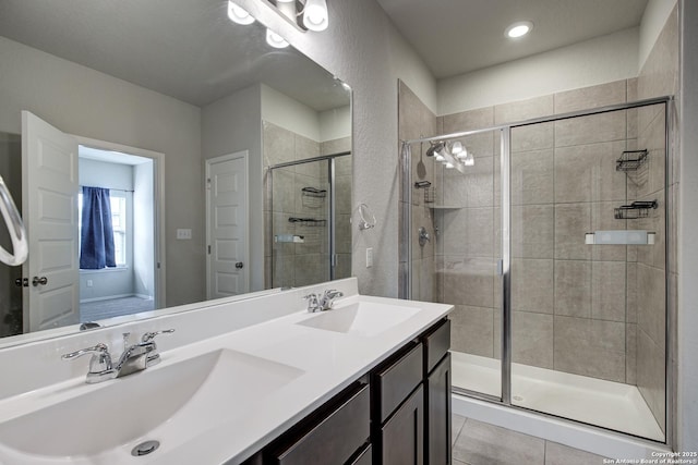 bathroom with double vanity, a stall shower, tile patterned flooring, and a sink