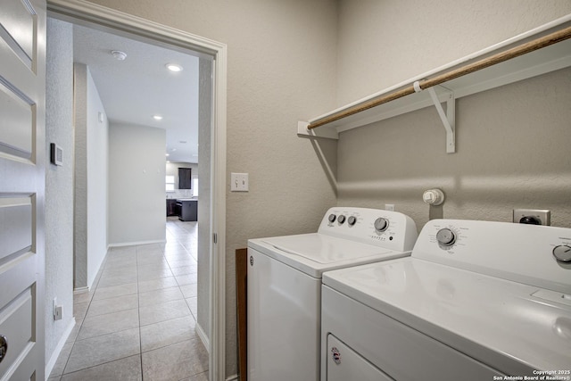 laundry area with light tile patterned floors, laundry area, washer and clothes dryer, and a textured wall