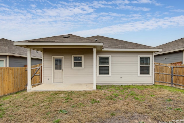 back of house featuring a shingled roof, a lawn, a patio area, and a fenced backyard