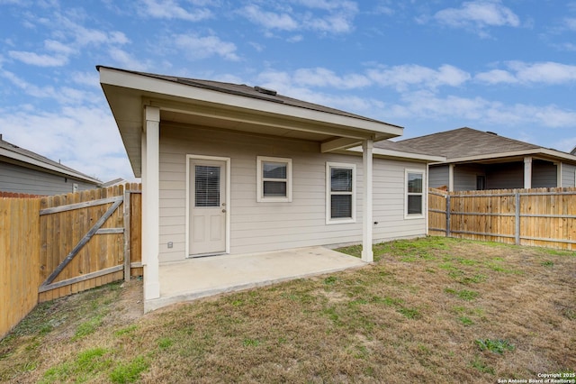 back of property featuring fence, a lawn, and a patio