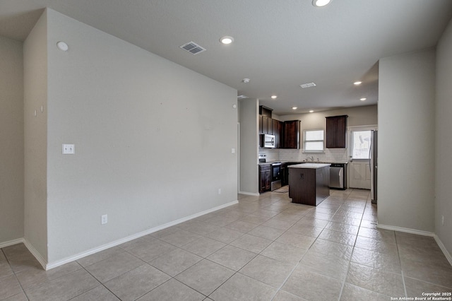 kitchen with visible vents, a kitchen island, stainless steel appliances, light countertops, and backsplash