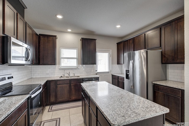 kitchen featuring dark brown cabinets, appliances with stainless steel finishes, a sink, and a center island