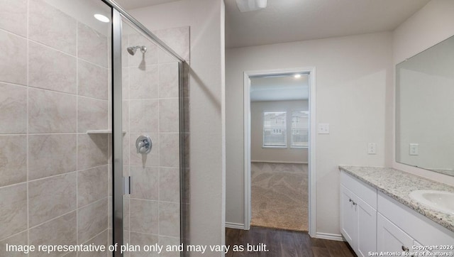 full bathroom with a stall shower, baseboards, wood finished floors, and vanity