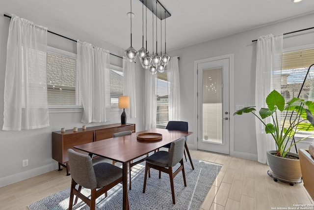 dining space with baseboards, plenty of natural light, and light wood-style floors