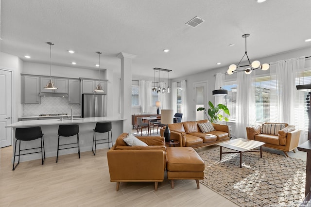 living area featuring recessed lighting, light wood-type flooring, visible vents, and a notable chandelier