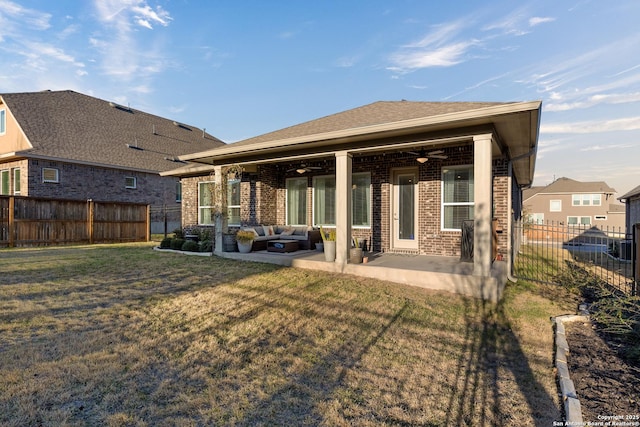 rear view of property featuring a patio, brick siding, a lawn, and a fenced backyard