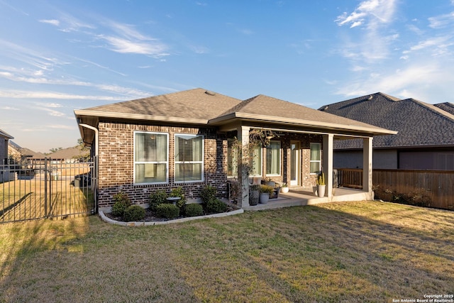 back of house with a yard, a shingled roof, fence, and brick siding