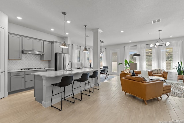 kitchen with stainless steel appliances, gray cabinets, light countertops, visible vents, and hanging light fixtures