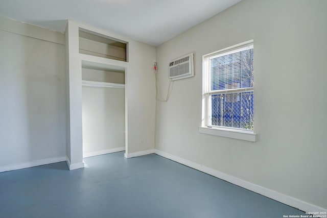 unfurnished bedroom featuring baseboards, multiple windows, a wall mounted air conditioner, and finished concrete floors