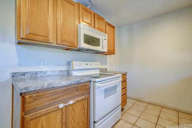 kitchen featuring light countertops, white appliances, light tile patterned flooring, and baseboards