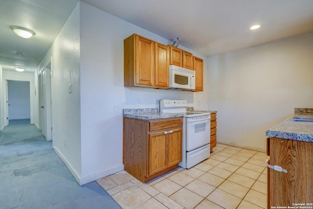 kitchen with brown cabinets, white appliances, light countertops, and baseboards