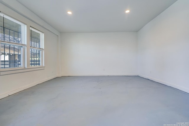 spare room featuring concrete flooring, baseboards, and recessed lighting