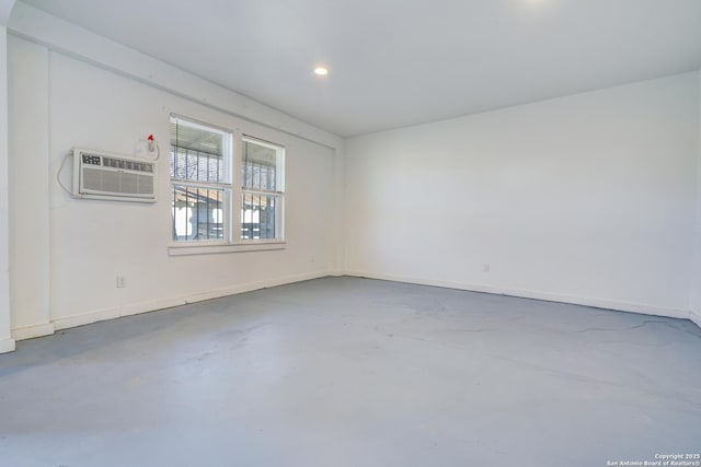 unfurnished room with concrete floors, baseboards, an AC wall unit, and recessed lighting