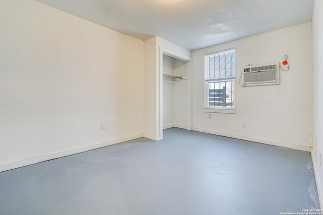 unfurnished room featuring finished concrete flooring, baseboards, and a wall mounted AC