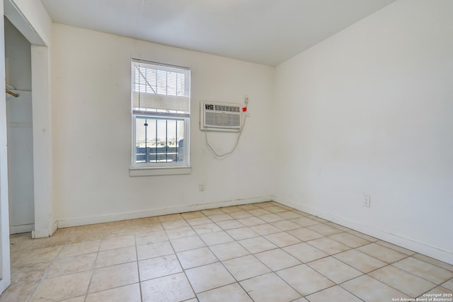 spare room with a wall unit AC, baseboards, and light tile patterned floors