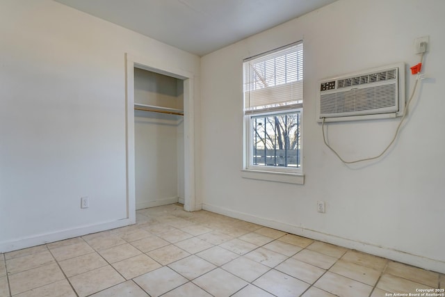 unfurnished bedroom featuring an AC wall unit, a closet, and baseboards