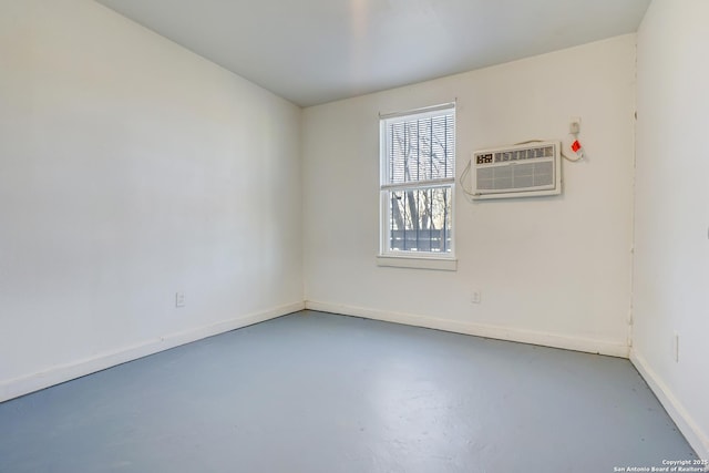 unfurnished room featuring concrete flooring, a wall unit AC, and baseboards