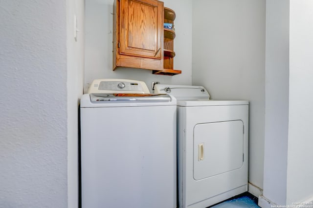 clothes washing area featuring cabinet space and washer and clothes dryer