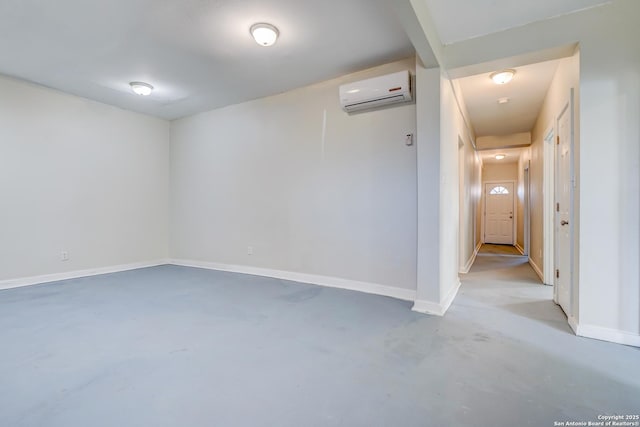 spare room featuring concrete flooring, a wall mounted air conditioner, and baseboards