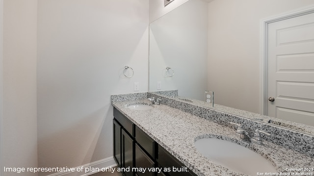 bathroom featuring double vanity, baseboards, and a sink