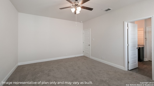 spare room with dark colored carpet, visible vents, ceiling fan, and baseboards