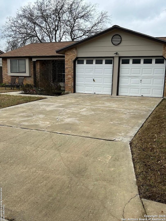 view of front of property featuring driveway, an attached garage, and brick siding