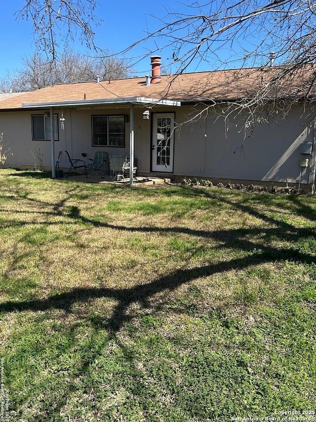 back of property with a chimney and a yard