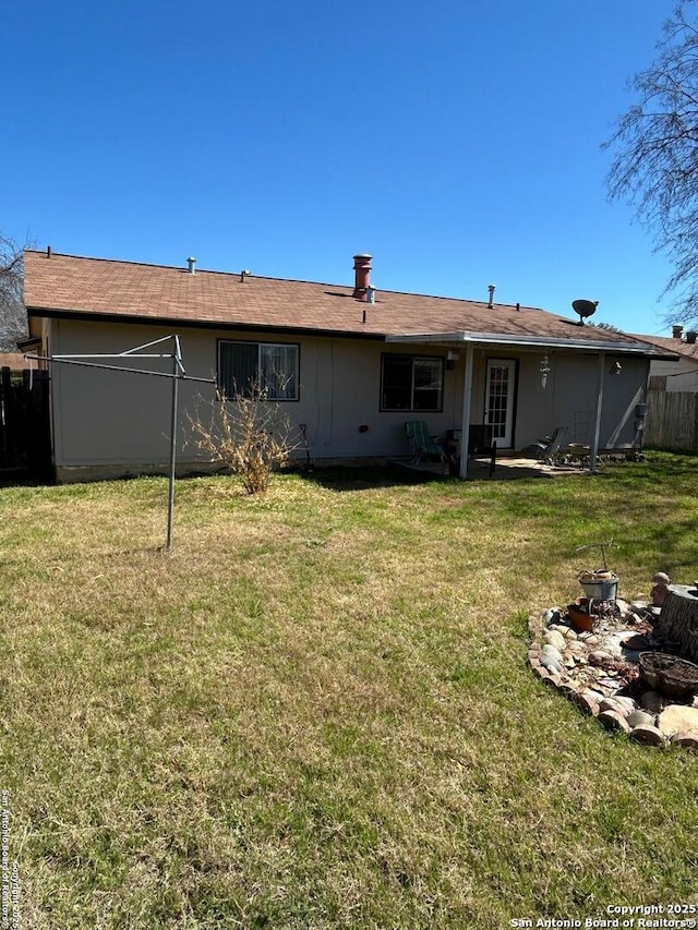 rear view of property featuring a lawn and fence