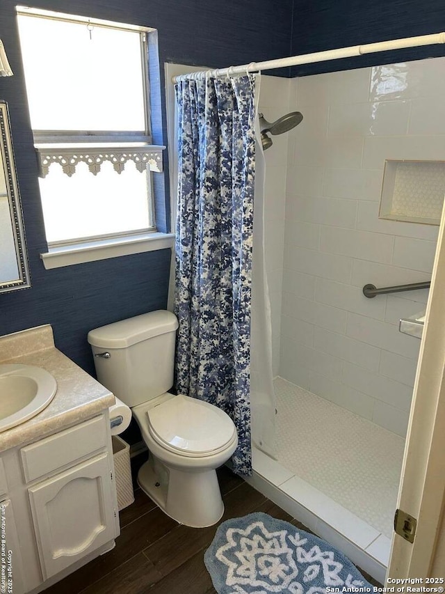 bathroom with toilet, a shower stall, vanity, and wood finished floors