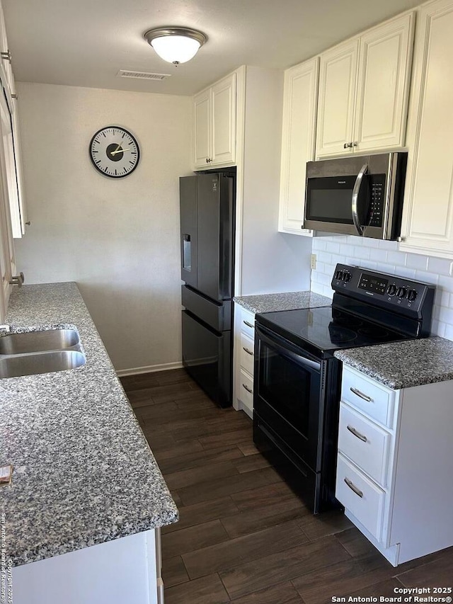 kitchen featuring white cabinets, stainless steel microwave, black range with electric stovetop, fridge with ice dispenser, and a sink