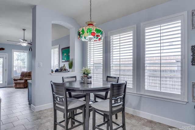 dining area with arched walkways, vaulted ceiling, a ceiling fan, and baseboards