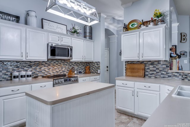 kitchen with decorative backsplash, white cabinets, appliances with stainless steel finishes, ornamental molding, and light countertops