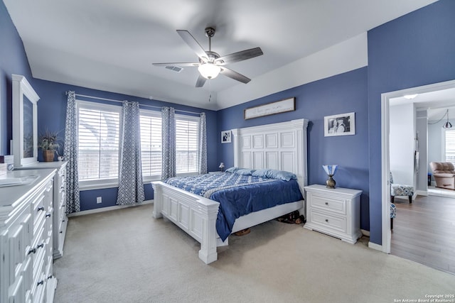 bedroom featuring ceiling fan, light colored carpet, visible vents, and baseboards