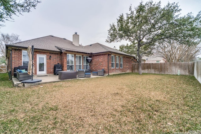 back of house featuring an outdoor living space, brick siding, a patio, and a chimney