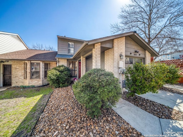 view of front of home featuring roof with shingles and brick siding