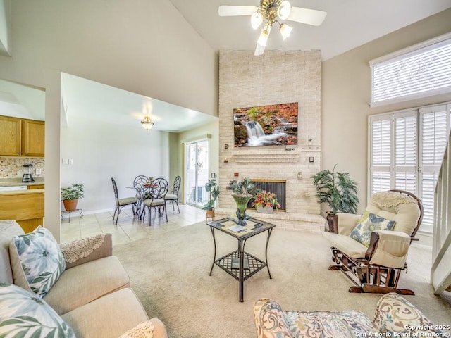 living area with a brick fireplace, a high ceiling, light tile patterned flooring, and a healthy amount of sunlight