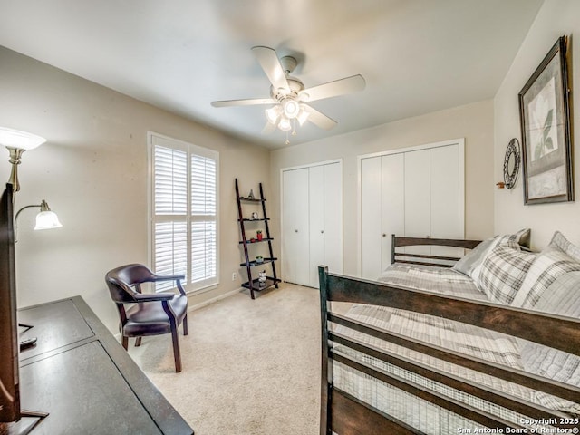 bedroom with multiple closets, light colored carpet, baseboards, and a ceiling fan