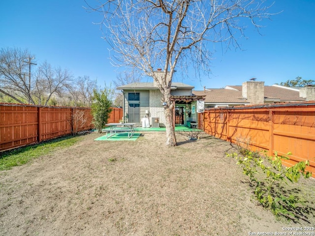 rear view of house featuring a patio area, a fenced backyard, and brick siding