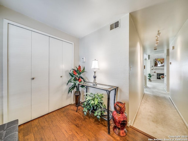 hall with baseboards, visible vents, and hardwood / wood-style floors