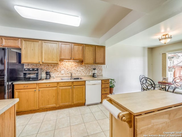 kitchen with light countertops, decorative backsplash, freestanding refrigerator, a sink, and dishwasher