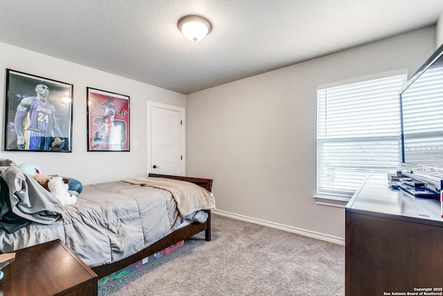 bedroom featuring light colored carpet, a textured ceiling, and baseboards