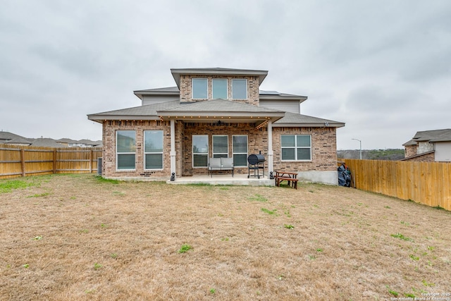 back of property featuring a patio area, a fenced backyard, a yard, and brick siding