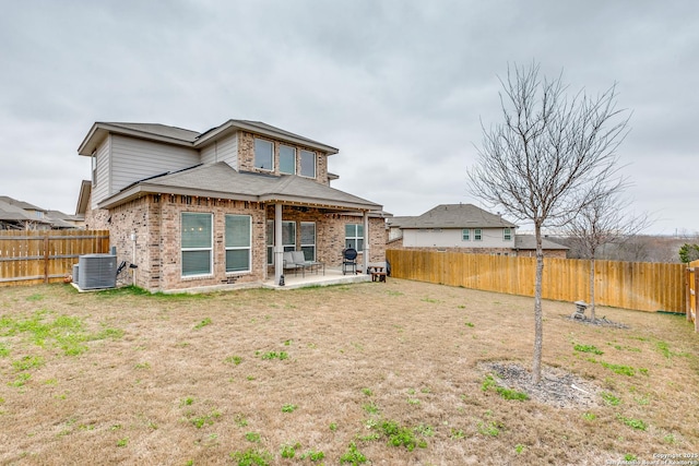 back of house with central air condition unit, a patio area, a fenced backyard, and brick siding