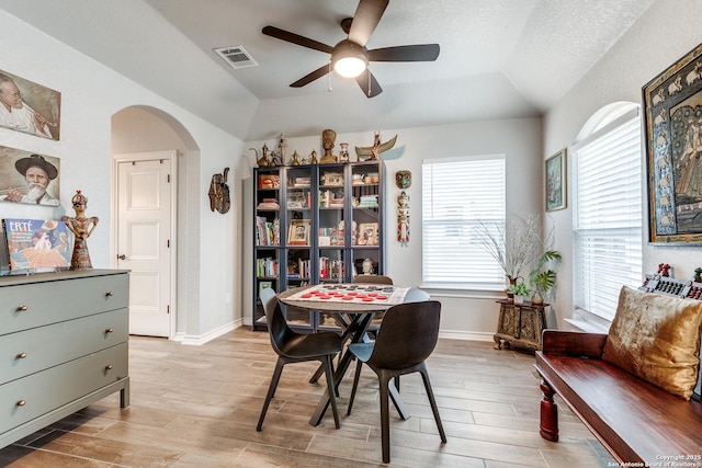 dining room with arched walkways, a tray ceiling, light wood-type flooring, and visible vents