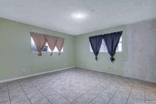 unfurnished room featuring a textured ceiling, baseboards, and light tile patterned floors