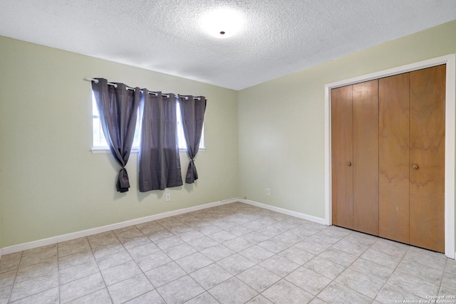 unfurnished bedroom with a textured ceiling, a closet, and baseboards