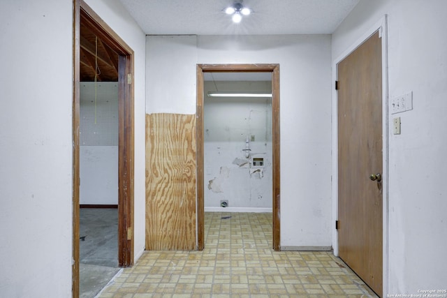 hallway featuring brick floor and baseboards